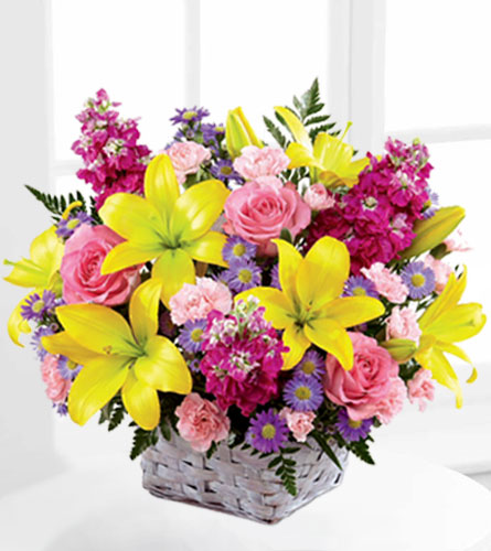 FTD's Basket of Bright Lights - yellow, pink and purple flowers arranged in a white woven basket.