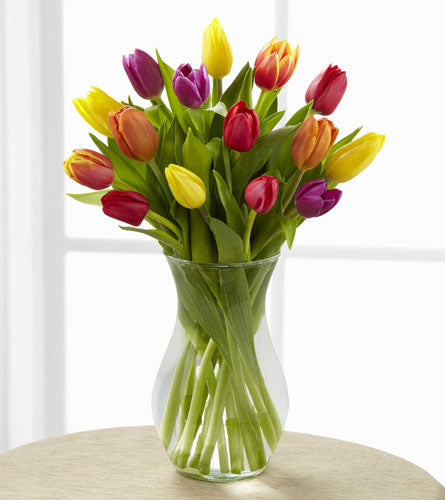 Mixed colorful tulip arrangement in a clear vase.