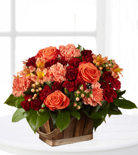 FTD's Abundant Harvest - arrangement of red and orange flowers in a wooden basket.