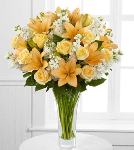 Admiration Luxury Bouquet - Floral design of yellow lilies and roses arranged with white stock in a clear glass vase.