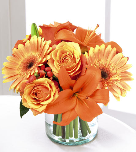 Simply Bewitching Bouquet - arrangement of orange and yellow flowers in a clear vase.