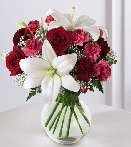 FTD's Enduring Romance Bouquet - arrangement of red roses, white lilies, and pink carnations in a clear vase.