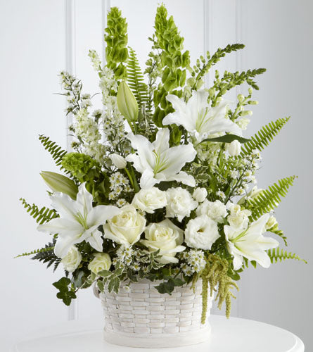 In Our Thoughts Arrangement - floral arrangement with white lilies and greenery in a white basket.