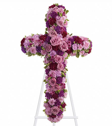 Deepest Faith - floral cross arrangement on a white stand with purple and pink flowers.