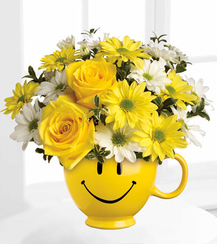 Teleflora's Be Happy Mug - yellow smiley face mug filled with yellow and white flowers.