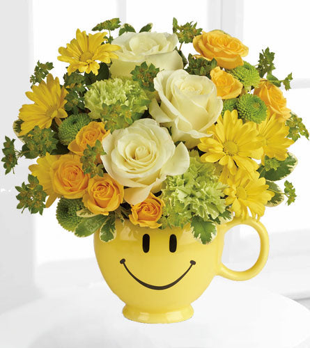 Teleflora's You Make Me Smile Bouquet - yellow smiley face mug filled with of yellow, white and green flowers.