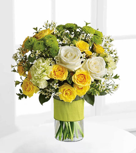Your Sweet Smile - Bouquet of yellow and white roses with wax flowers in a clear vase with a lime ribbon.