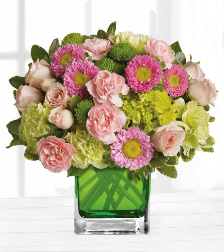 Make Her Day - Mixed pink and green flowers arranged with greenery in a green cube vase.
