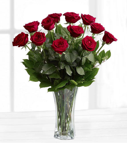 A Dozen Red Roses - Bouquet of a dozen red roses with greenery in a clear vase.