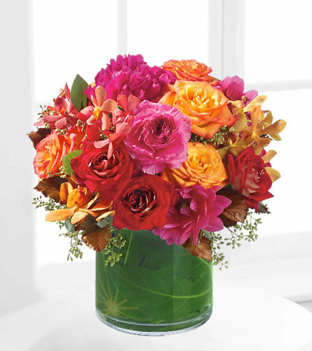 Hot Couture - bouquet of mixed colourful roses with other flowers in a leaf wrapped vase.