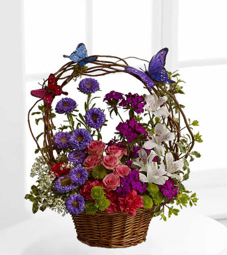 The Dancing Butterflies Basket - Floral arrangement of pink, lavender and white flowers with butterflies in a woven basket.