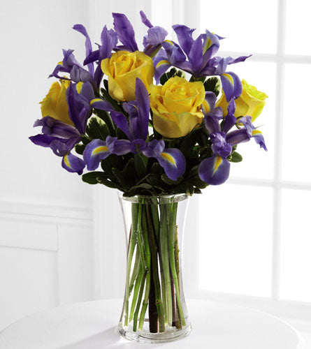 Sunlit Treasures Bouquet - floral arrangement of yellow roses and purple irises in a clear vase.