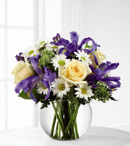 The Sweet Beginnings - Bouquet of purple irises, white roses, and daisies in a clear bubble bowl vase.