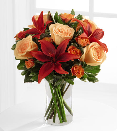 Tigress Bouquet - peach roses, red lilies, and orange spray roses in a clear glass vase.