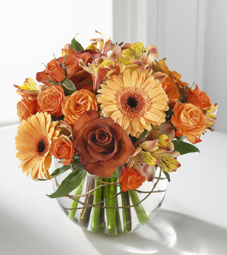 Natural Elegance Bouquet - arrangement of orange and yellow flowers in a clear vase.
