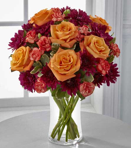 The Autumn Treasures Bouquet - orange roses and mini carns with purple chrysanthemums in a clear vase