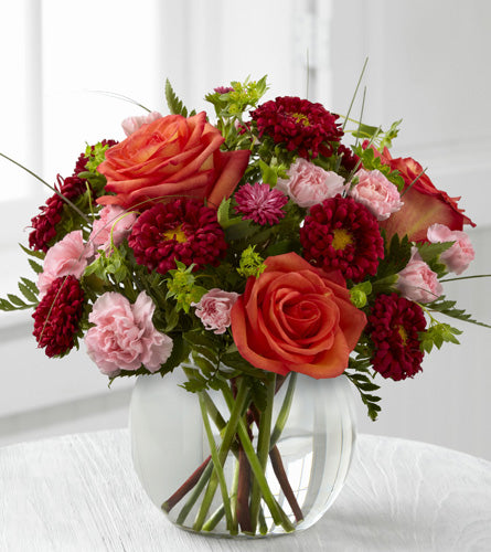 Colour Rush by Better Homes & Gardens - Bouquet of red and pink flowers with orange roses in a clear bubble vase.