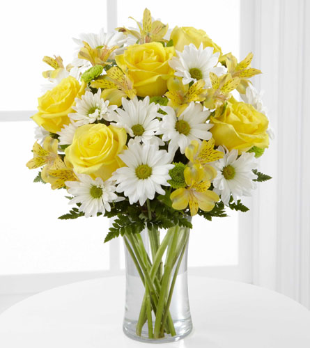 Sunny Sentiments - Bouquet of yellow roses and lilies with white daisies in a clear vase.