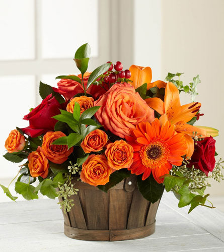 Nature's Bounty - bouquet of orange and red flowers in a brown wooden basket.