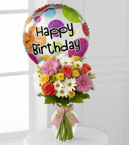FTD's Birthday Cheer Bouquet -  arrangement of flowers in a clear vase with a decorative bow and a 'Happy Birthday' balloon attached.