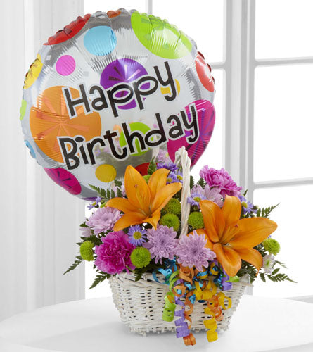 Happy Blooms -  mixed flower arrangement in a white basket with a "Happy Birthday" balloon attached.