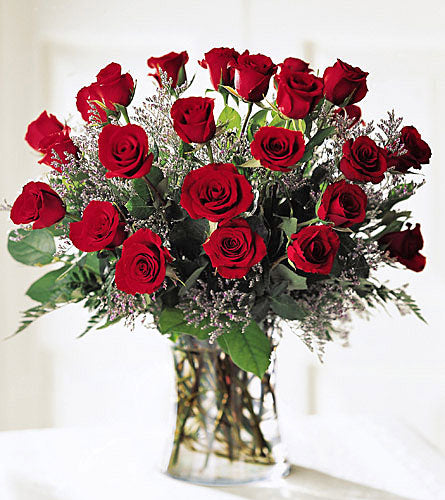 Abundant Rose Bouquet - arrangement  of two dozen red roses with wax flowers and greenery in a clear vase.