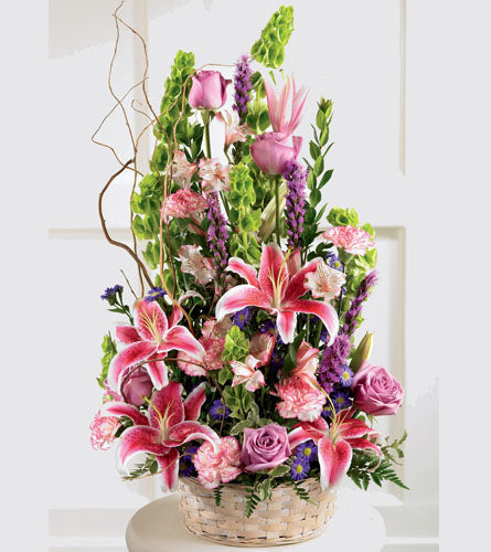 All Things Bright Arrangement - arrangement of flowers in a basket with pink lilies and roses.