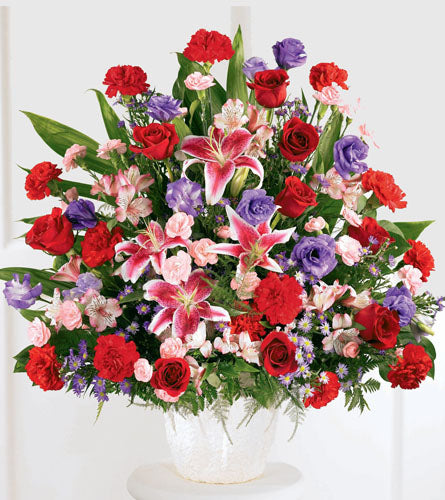 Eternal Solace Arrangement - bouquet of colourful flowers including red roses, pink lilies, and purple hydrangeas in a clear vase.