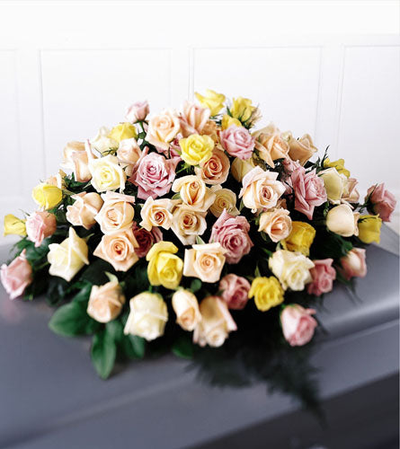 Peaceful Tribute Casket Spray - bouquet of multicolored roses with greenery.