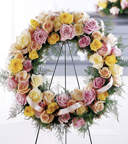 Vibrant Sympathy Wreath - floral wreath with pink, yellow, and white roses on a stand.