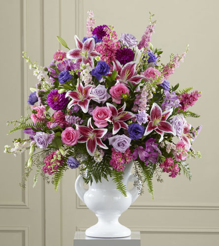 FTD's Peaceful Tribute Arrangement - colourful funeral design with pink, purple and blue flowers displayed in a white urn.