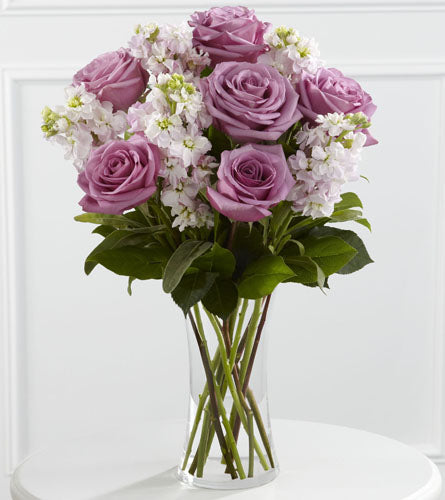 All Things Bright Bouquet - arrangement of purple and white flowers in a clear vase.