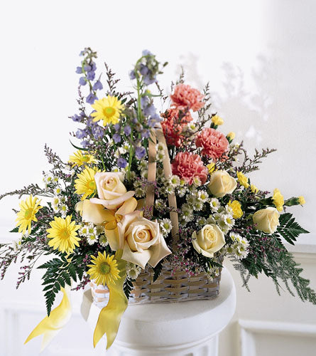 Loving Remembrance Basket - floral arrangement in a basket with yellow, pink, and green flowers.