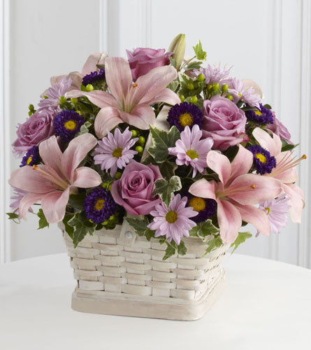 Loving Sympathy Basket - floral arrangement with pink lilies and purple flowers in a white woven basket.