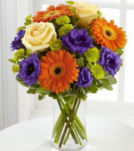 Rays of Sunshine Arrangement - bouquet of flowers with orange, purple, and yellow flowers in a clear vase.