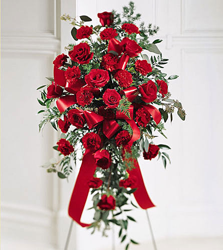 Sweet Thoughts Standing Spray - bouquet of red roses with greenery and red ribbons on a standing frame.