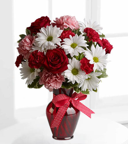 Hugs and Kisses - Bouquet of red, pink, and white flowers in a red glass vase with a red bow.