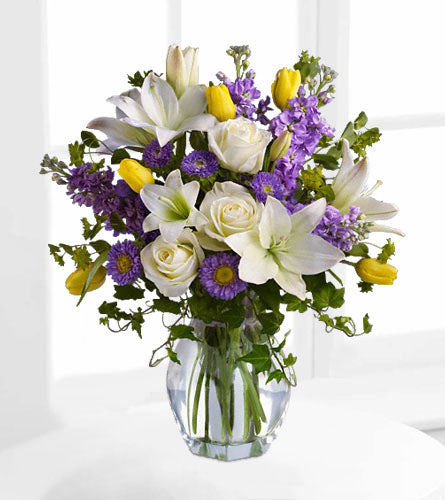 Spring Waltz - bouquet of flowers with white, purple and yellow flowers in a clear vase.