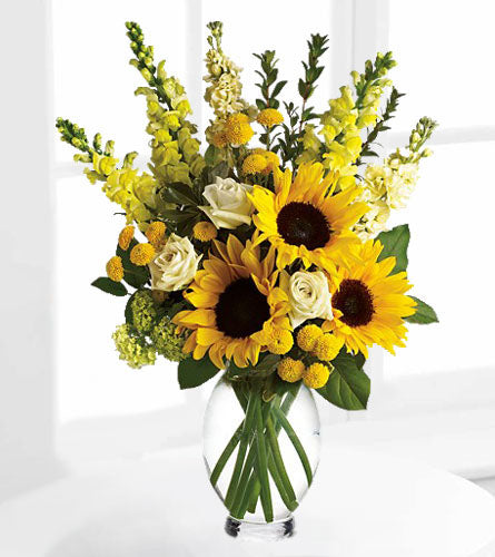 Here Comes The Sun by Teleflora - bouquet of sunflowers. bright yellow and white flowers in a clear vase.
