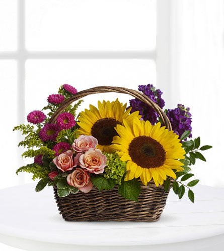 Picnic in the Park - floral arrangement with sunflowers, roses and mixed flowers in a woven brown basket.
