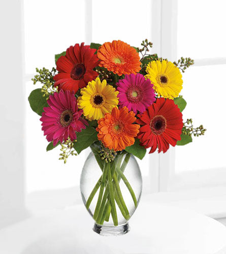 Teleflora's Gerbera Brights - bouquet of colorful gerbera daisies in a clear vase.