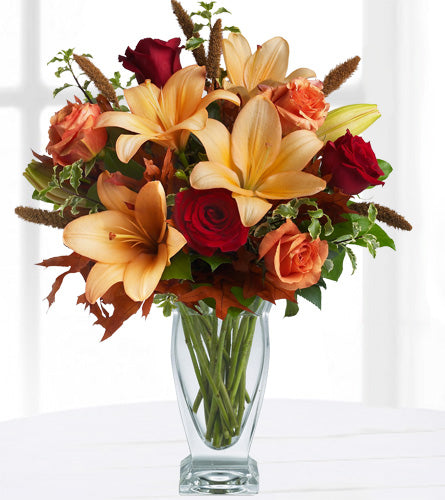 Teleflora's Fall Fantasia - bouquet of flowers with red, orange, and yellow flowers in a clear vase.