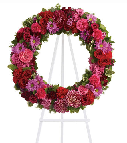 Infinite Love - floral wreath with red; pink and purple flowers on a white stand.