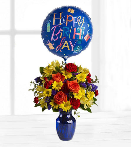 Fly Away Birthday Bouquet - colourful arrangement of flowers in a blue vase with a 'Happy Birthday' balloon.