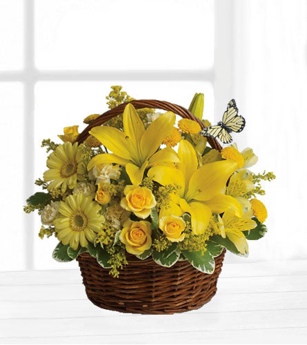 Basket Full of Wishes - yellow flowers with a butterfly arranged in a brown woven basket.