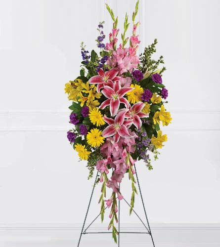 Rainbow of Remembrance Spray - standing funeral spray of bright mixed flowers displayed on an easel.