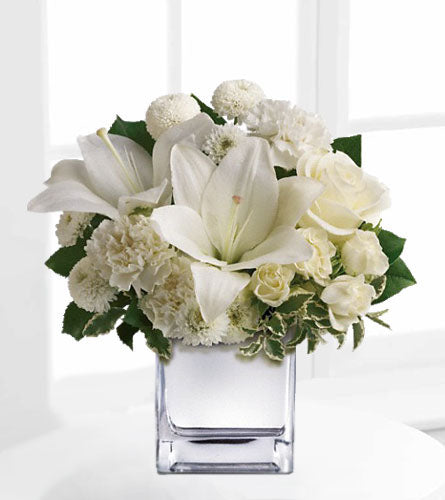 Peace & Joy - floral design of white lilies, carnations and spray roses in a clear cube.