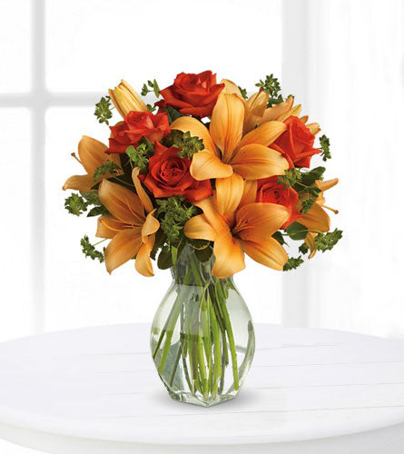 Fiery Lily and Rose - bouquet of orange lilies and red roses in a clear glass vase.