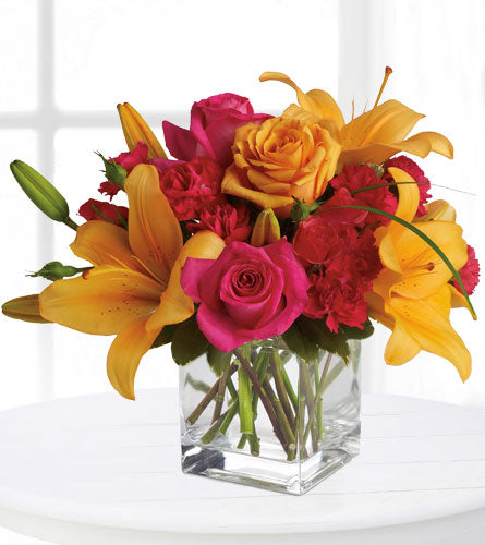 Uniquely Chic - Bouquet of pink and yellow flowers in a clear glass cube.