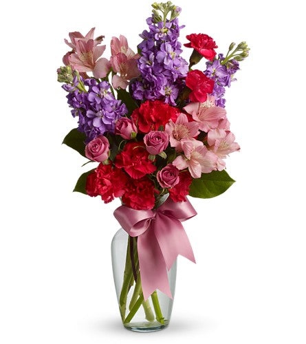 Jumping for Joy - bouquet of colourful flowers with a pink ribbon in a clear vase.